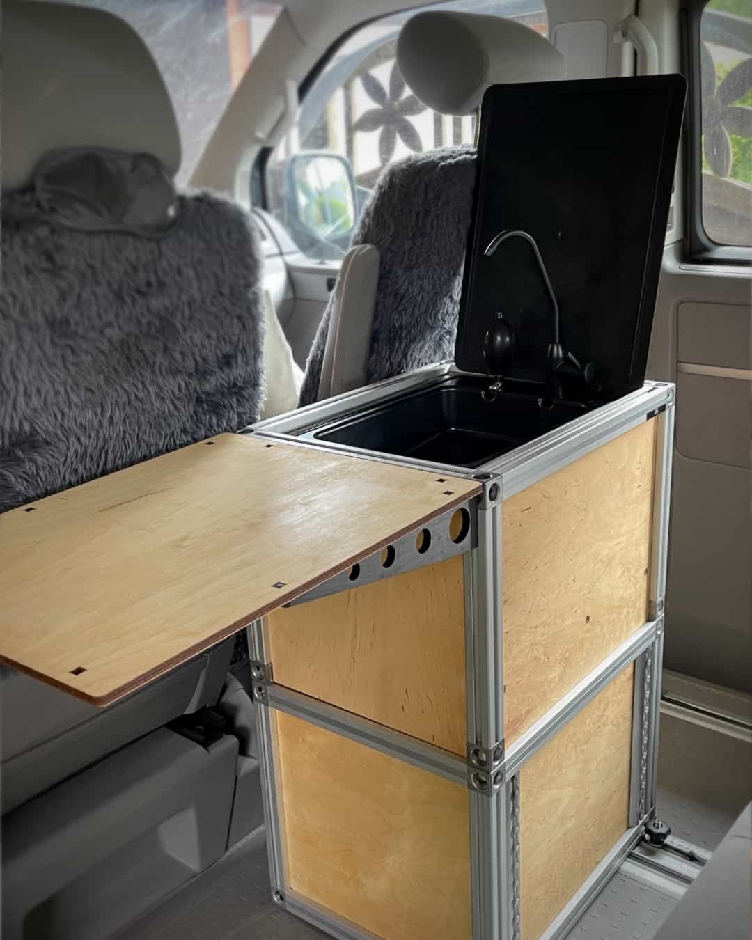 Eine Arbeitsfläche verbindet Spüle und Tisch im Campingausbau.