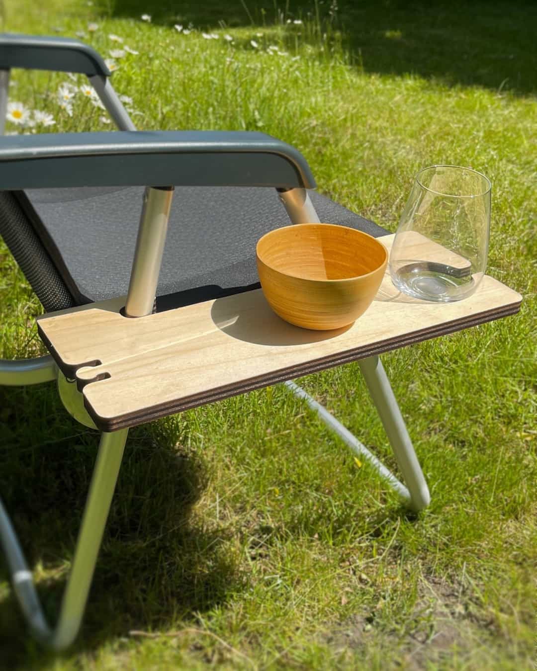 Folding chair with practical cup holder A glass stands on the shelf of a folding camping chair.